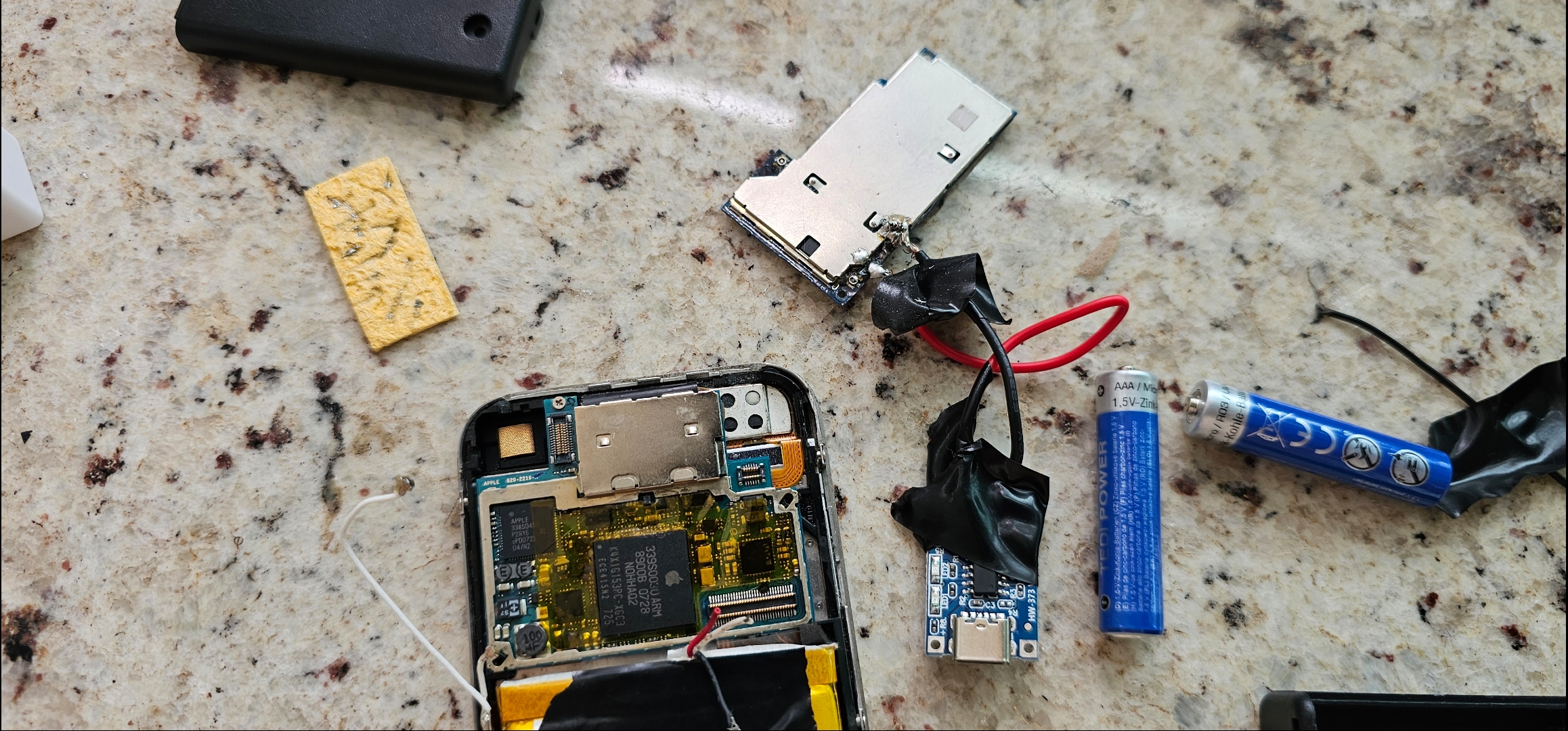 Disassembled iPhone 2G logic board and battery module on countertop
